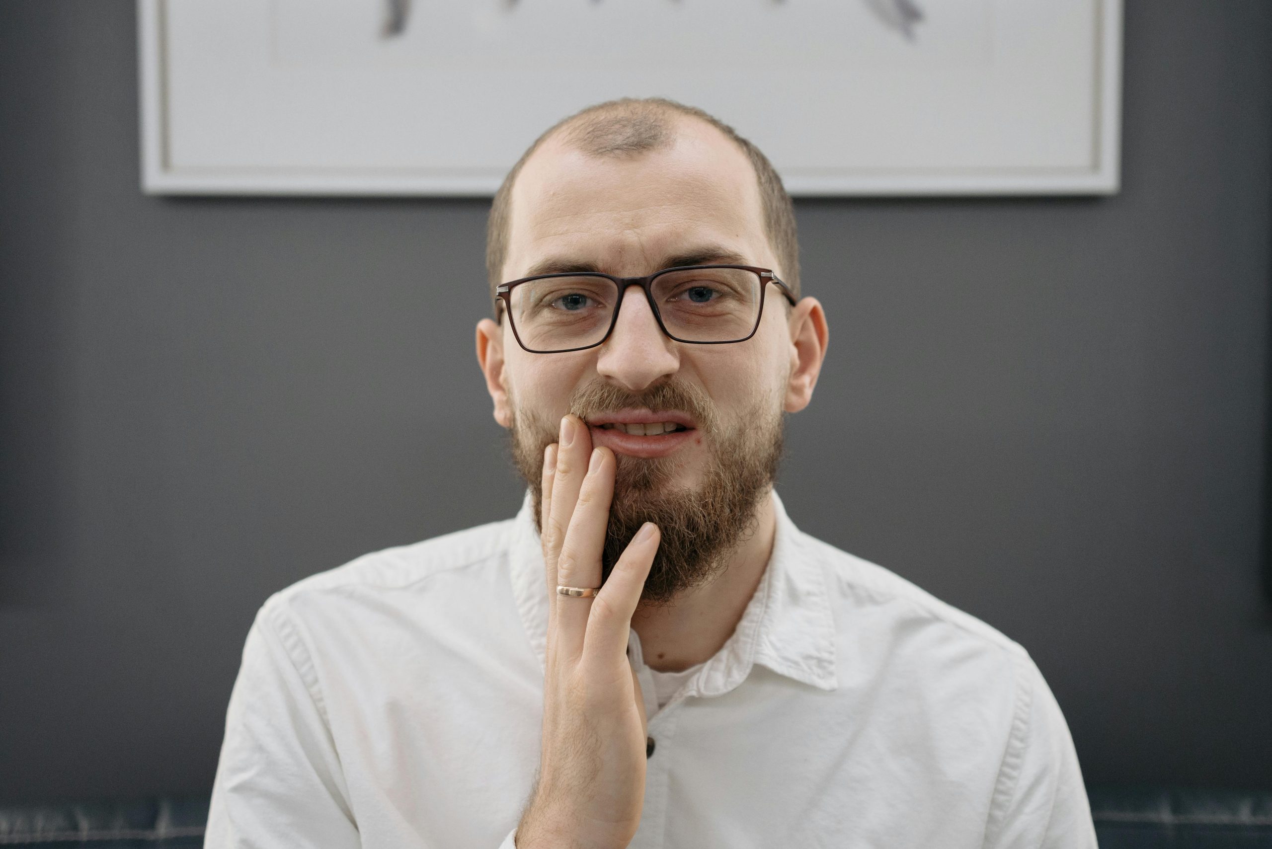 man touching the side of his mouth, showing signs of tooth pain
