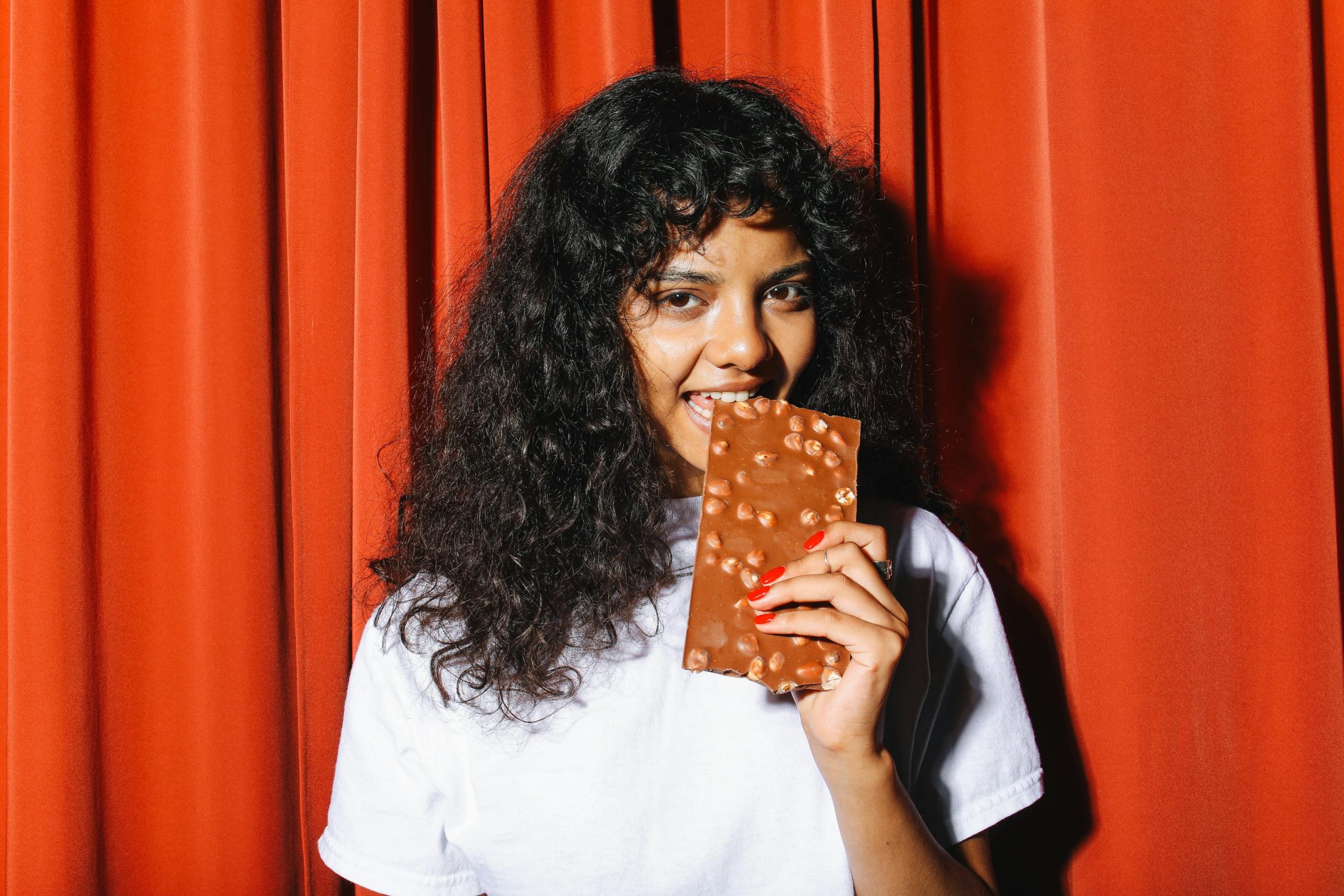 woman taking a bite of a chocolate bar